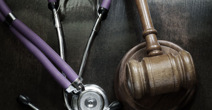 Stethoscope and gavel on wooden surface.