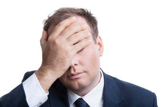 Person in suit holding head.