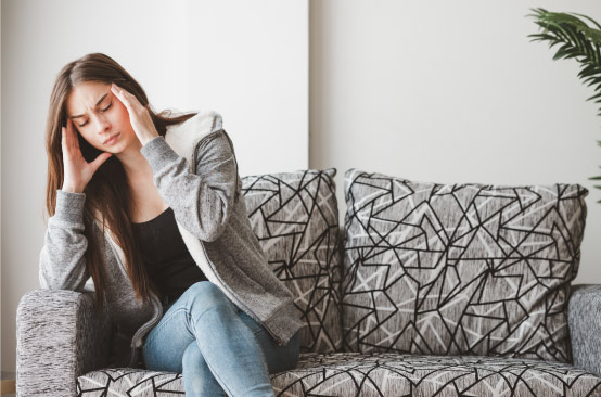 Person sitting on patterned couch with dizziness