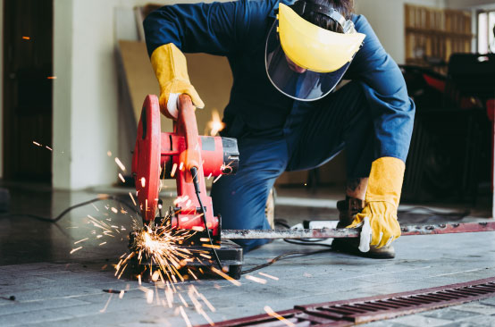 Worker cutting metal with circular saw.