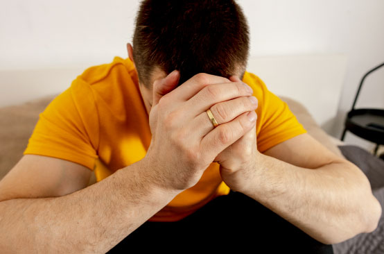 Person in yellow shirt, hands clasped.