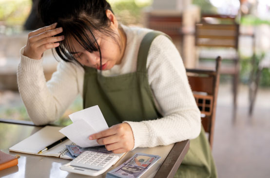 Woman calculating expenses with calculator.