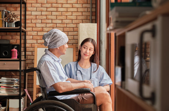 Elderly person in wheelchair with caregiver.