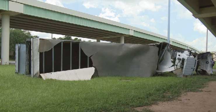 Semi-truck flips off I-110 in Pensacola, crashes in grass field below
